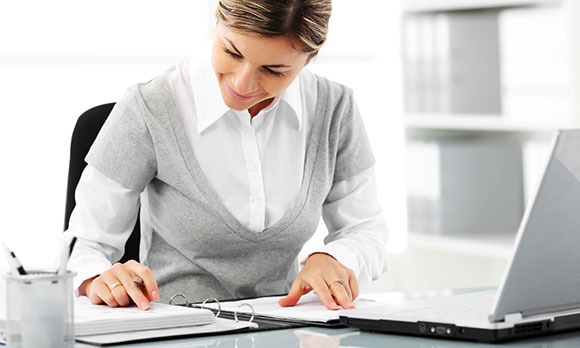 Woman sitting at desk in front of laptop.
